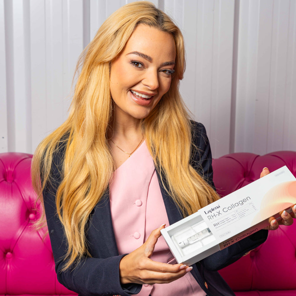 Woman holding a box of of RH-X Collagen Booster half opening the packet sat on a pink couch.