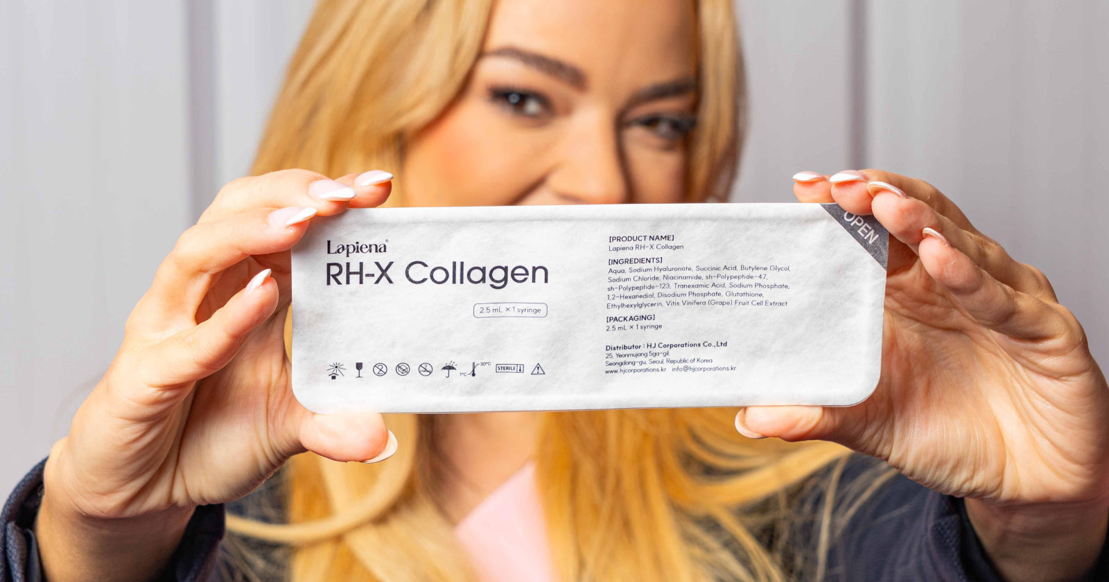 Woman holding a box of of RH-X Collagen Booster towards the camera